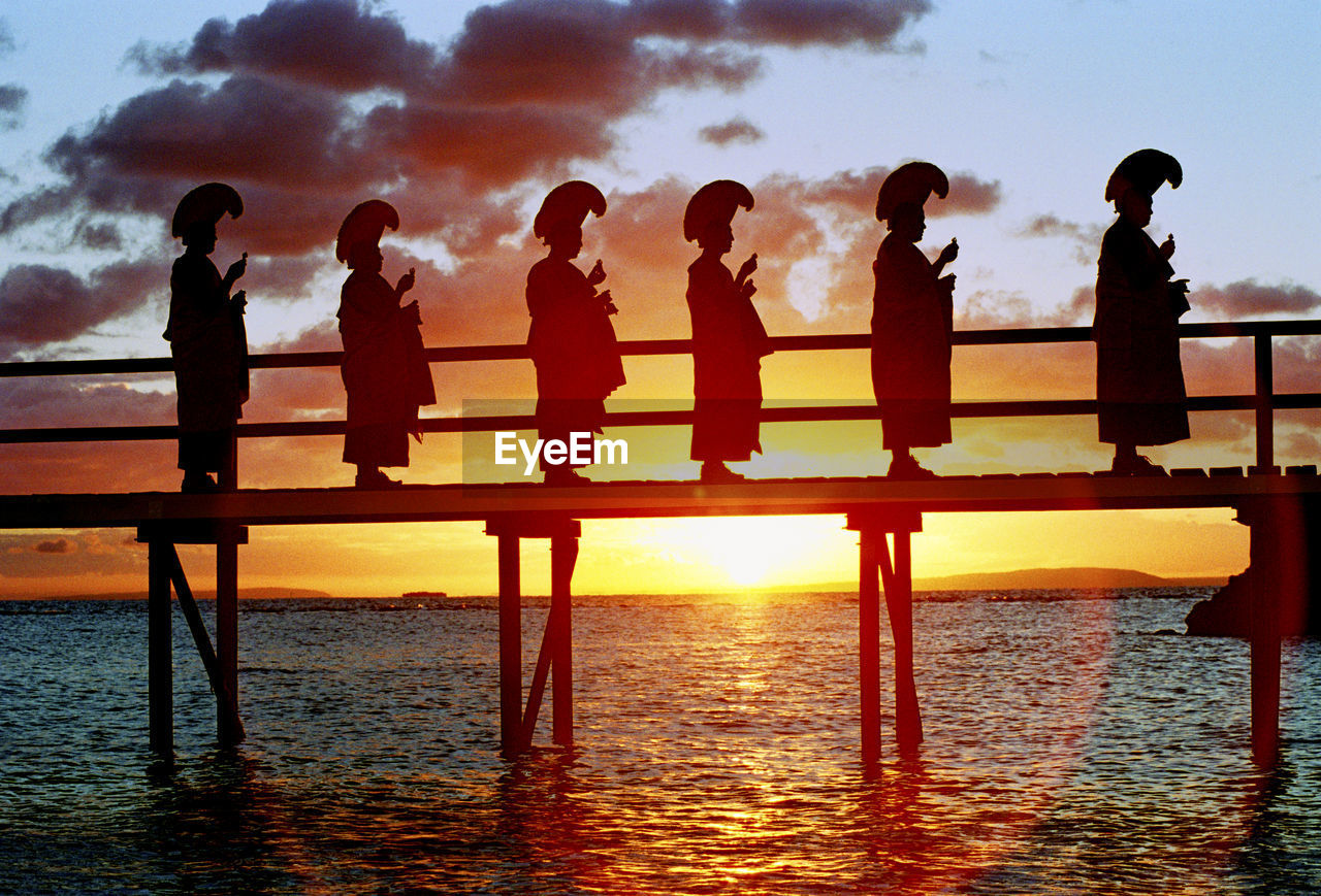 SILHOUETTE PEOPLE STANDING ON BEACH DURING SUNSET