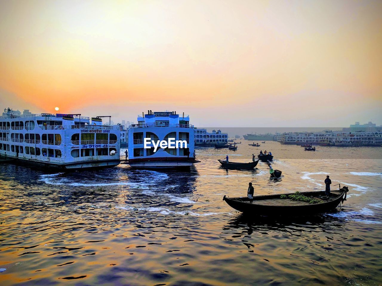 PEOPLE ON BOAT IN SEA AGAINST ORANGE SKY