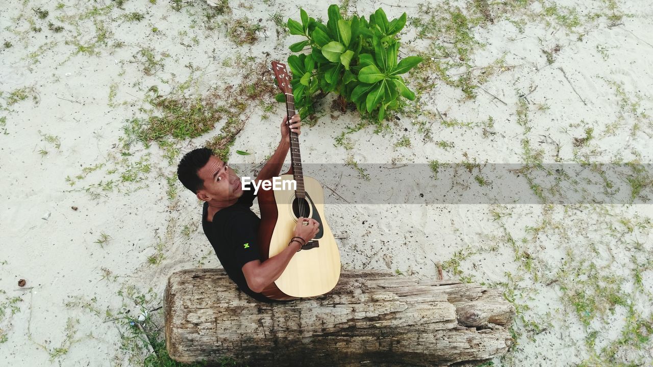 Portrait of mid adult man playing guitar at beach