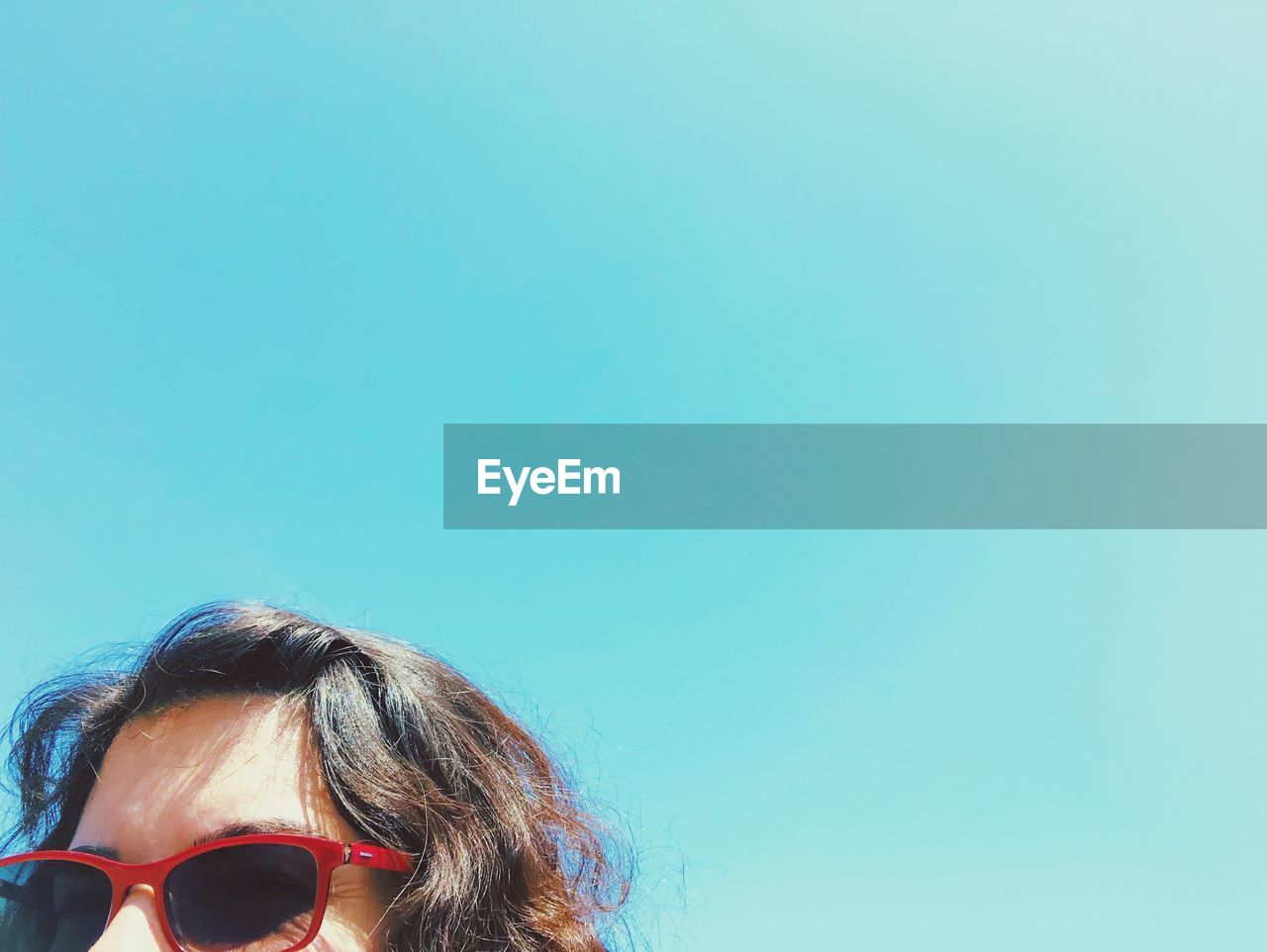 Close-up of woman wearing sunglasses against clear blue sky