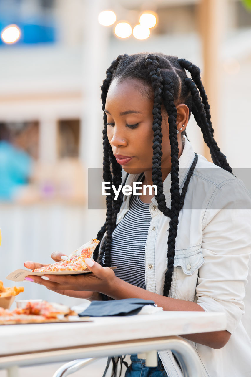 Woman holding pizza while sitting in restaurant