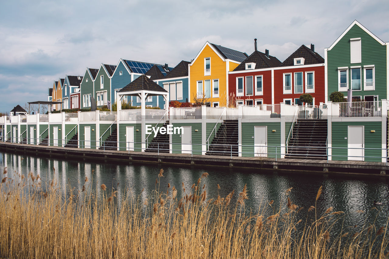 BUILDINGS BY LAKE AGAINST SKY