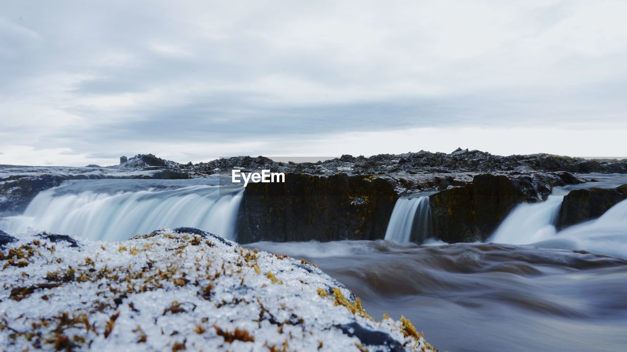 Scenic view of waterfall against sky