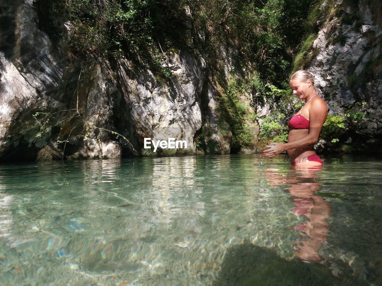 Side view of woman wearing bikini standing in lake