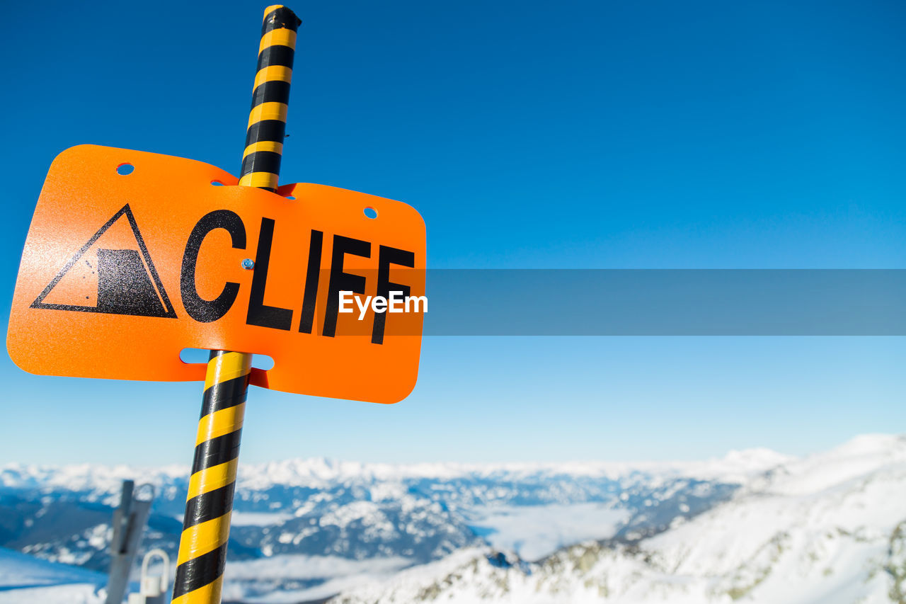 LOW ANGLE VIEW OF ROAD SIGNS AGAINST BLUE SKY