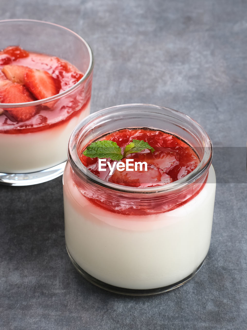 Sweet vanilla silky pudding dessert with strawberry sauce, sliced fresh strawberries and mint 
