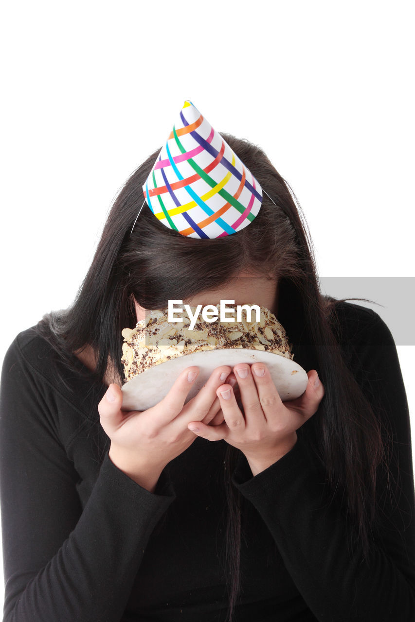 Woman applying cake on face against white background