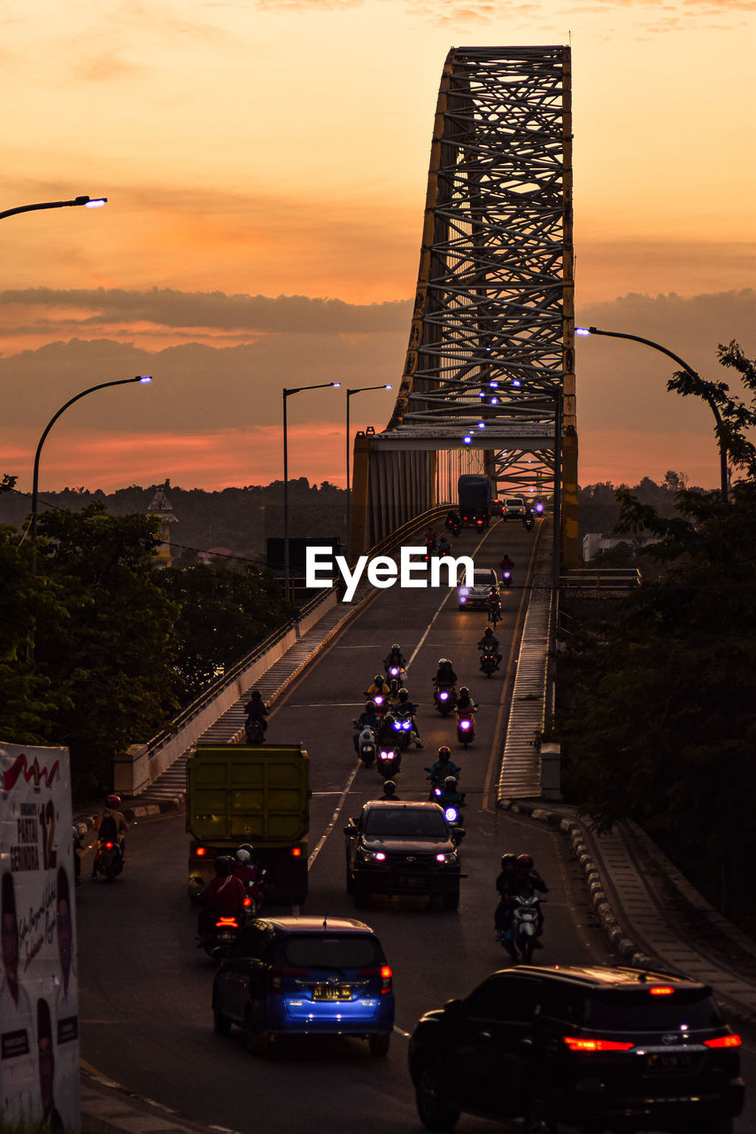 TRAFFIC ON ROAD IN CITY AGAINST SKY DURING SUNSET