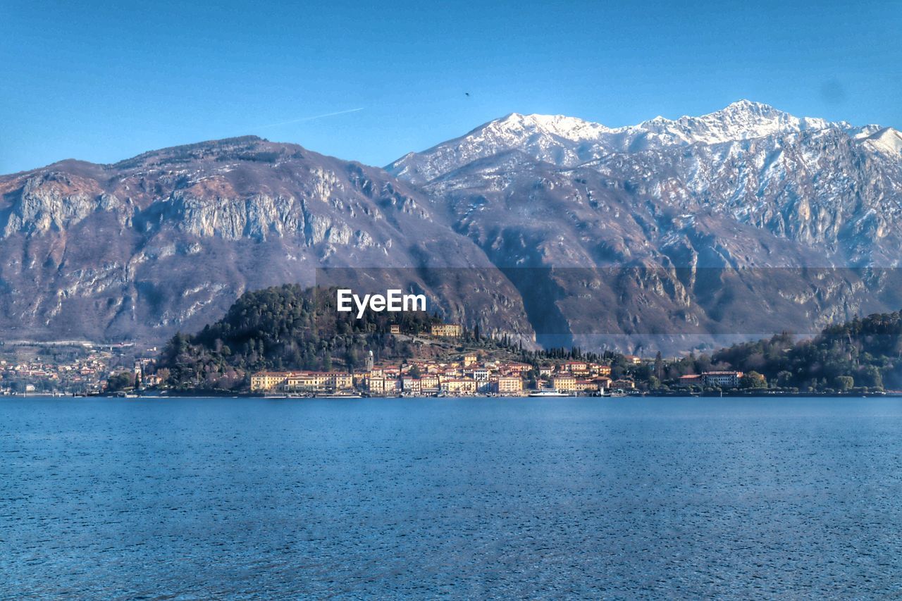 Scenic view of sea and mountains against blue sky