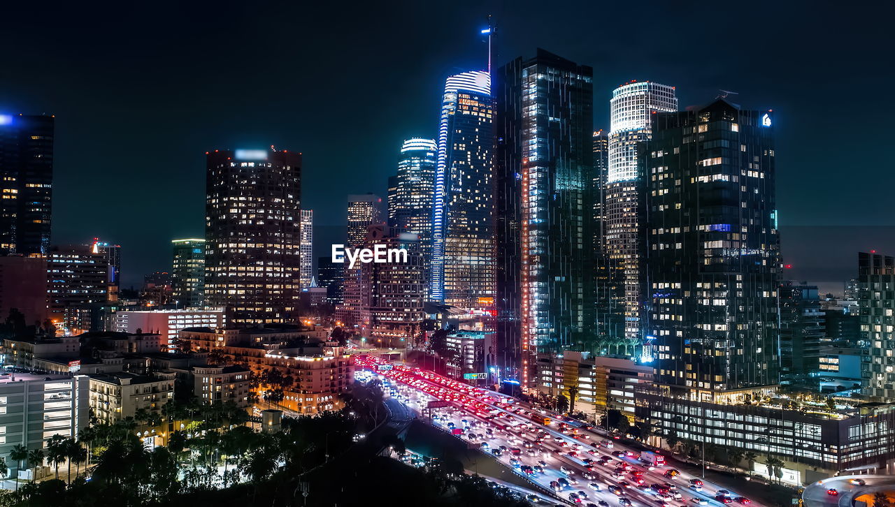 Illuminated buildings in city against sky at night