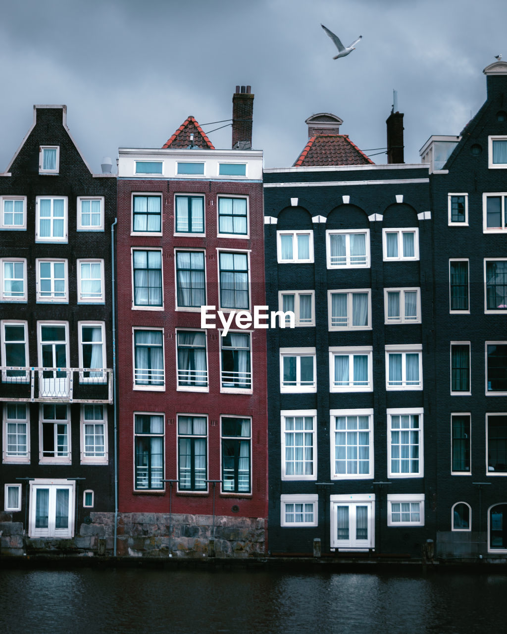 The unique houses of damrak on a cloudy day found in the heart of the dutch capital of amsterdam.