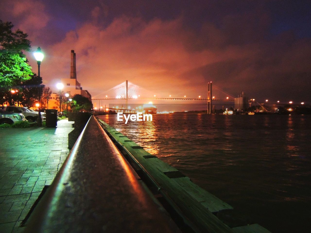 ILLUMINATED BRIDGE OVER RIVER IN CITY AT NIGHT