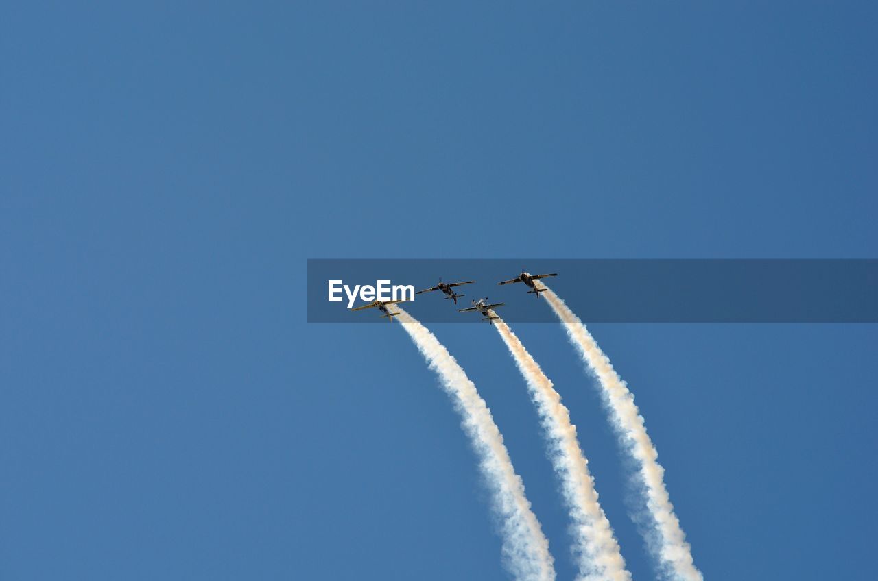 Low angle view of airplane flying against clear blue sky