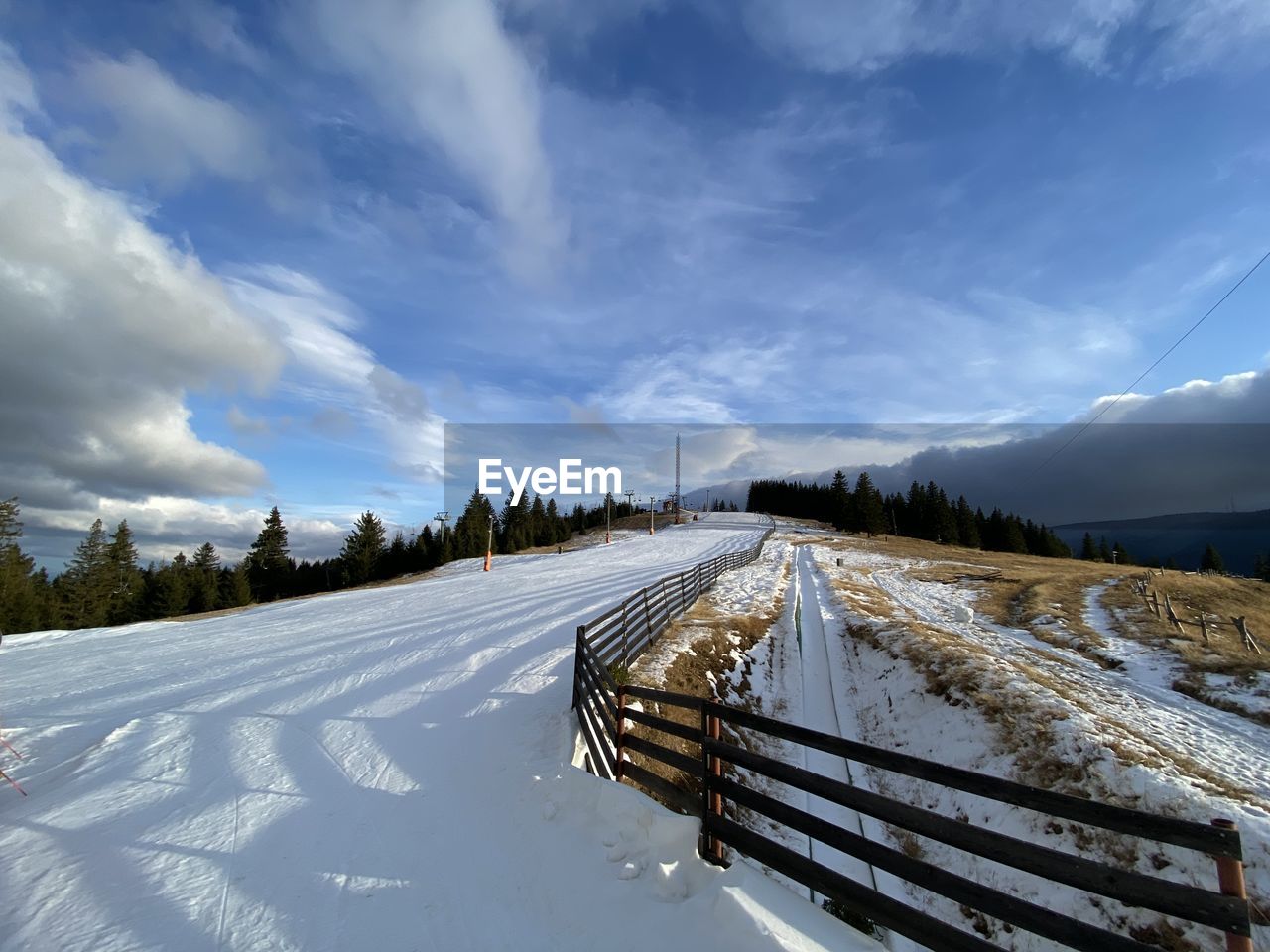 Snow covered road amidst land against sky