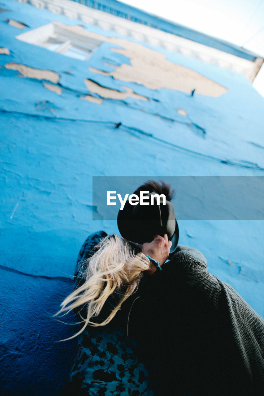 Low angle view of couple romancing against blue wall