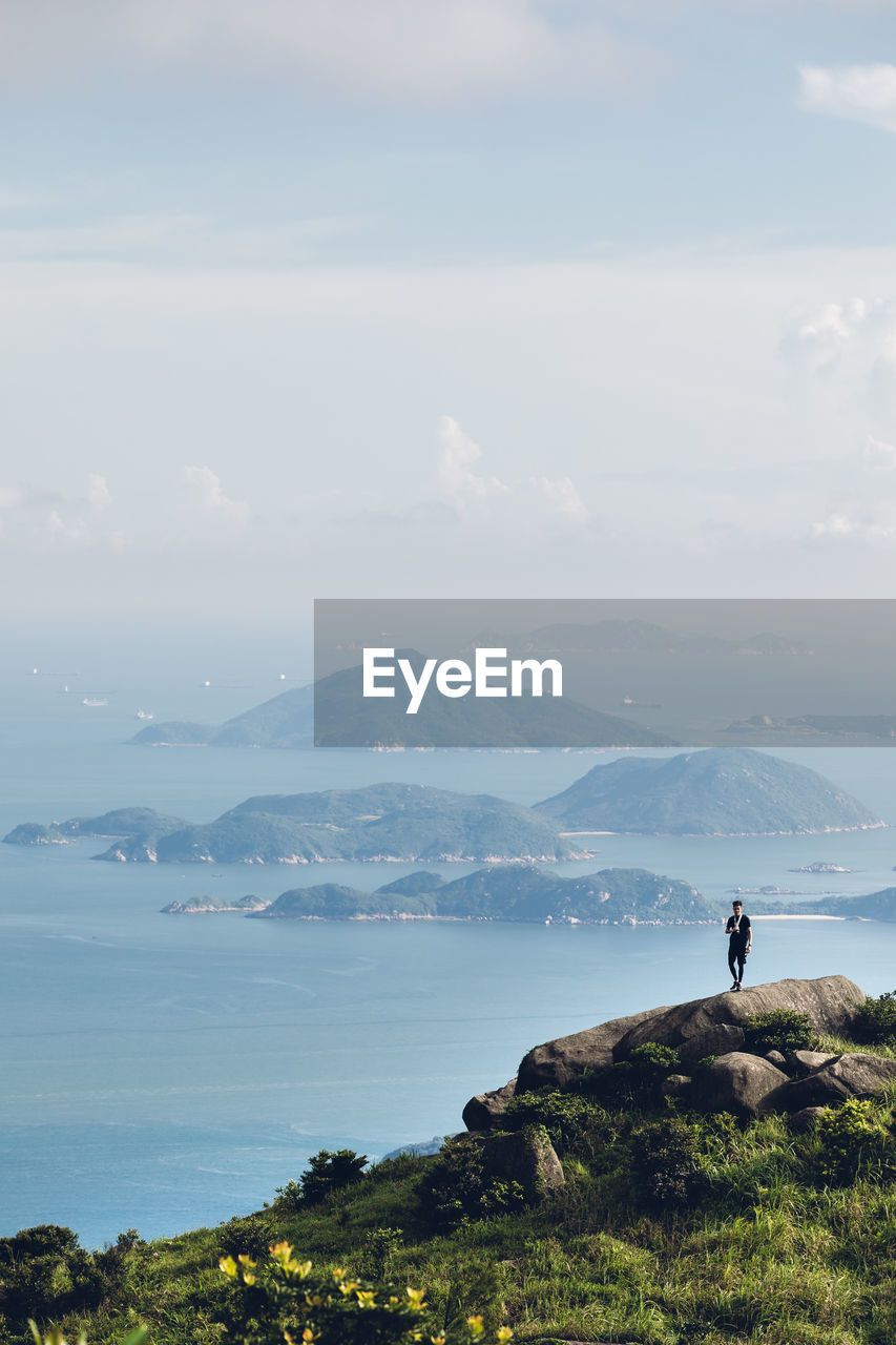 MAN LOOKING AT VIEW OF MOUNTAINS AGAINST SKY