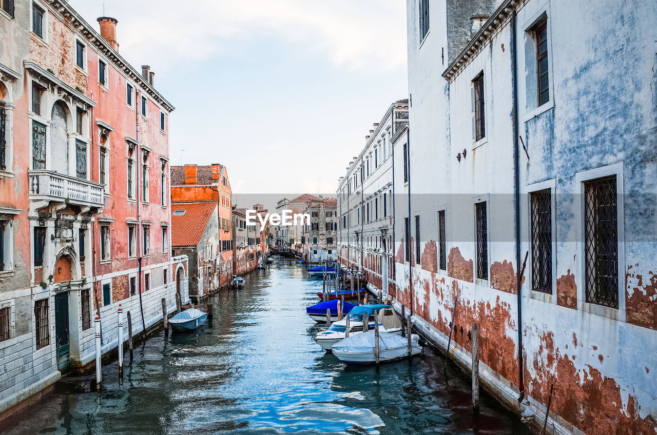 Boats moored in canal along built structures