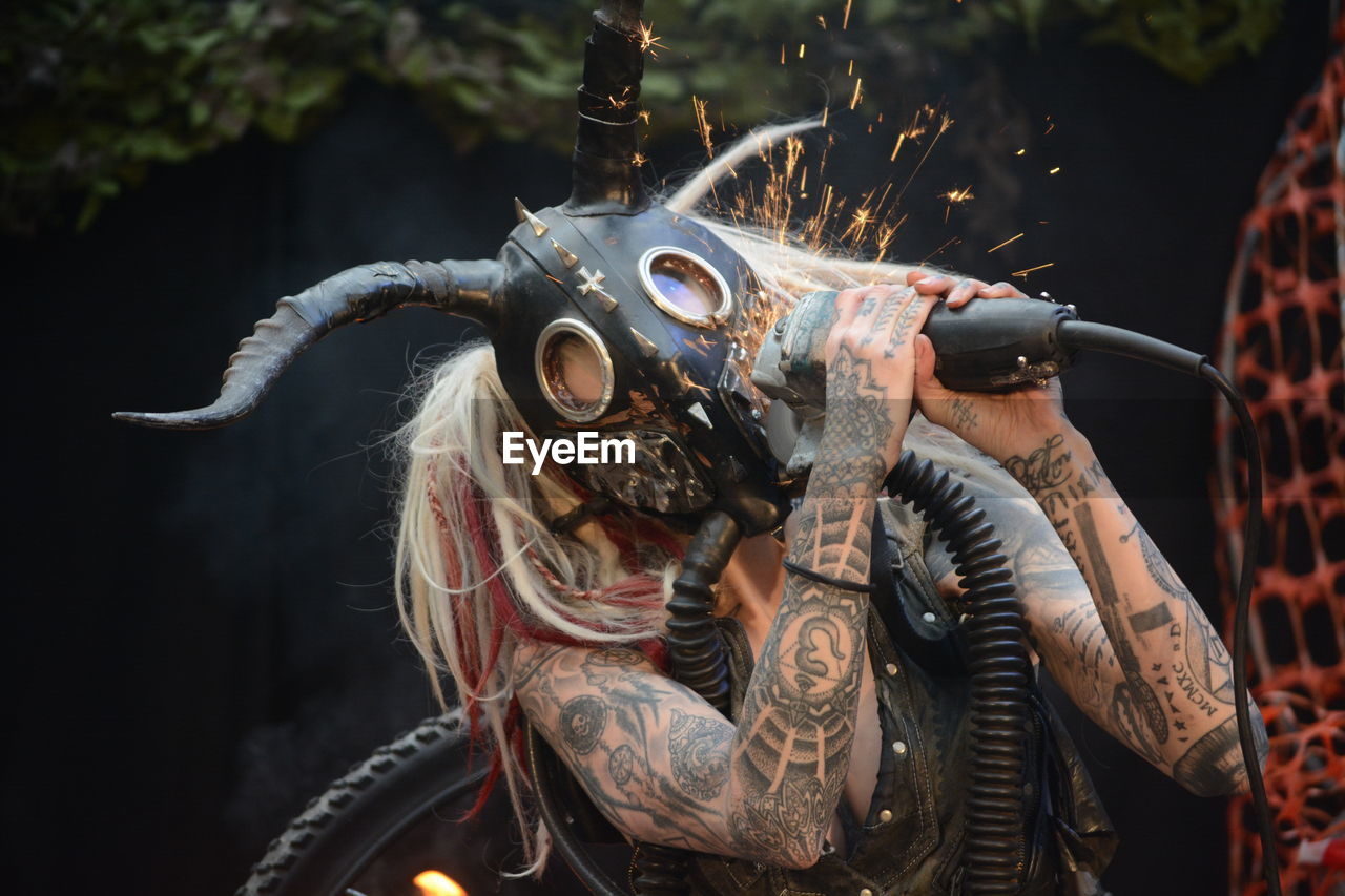 Woman cutting gas mask with machinery outdoors