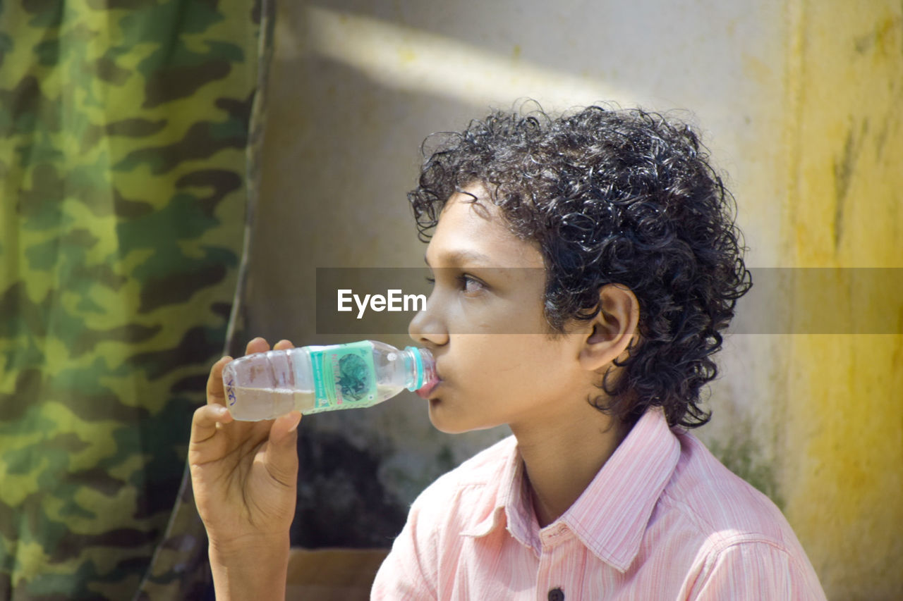 refreshment, drink, one person, drinking, food and drink, headshot, portrait, person, curly hair, women, child, water, holding, childhood, drinking water, cold drink, lifestyles, female, bottle, hairstyle, side view, adult, indoors, thirsty, looking, nature, human face, food, black hair, profile view, glass, relaxation, drinking glass, young adult, casual clothing, singing, brown hair, freshness, leisure activity