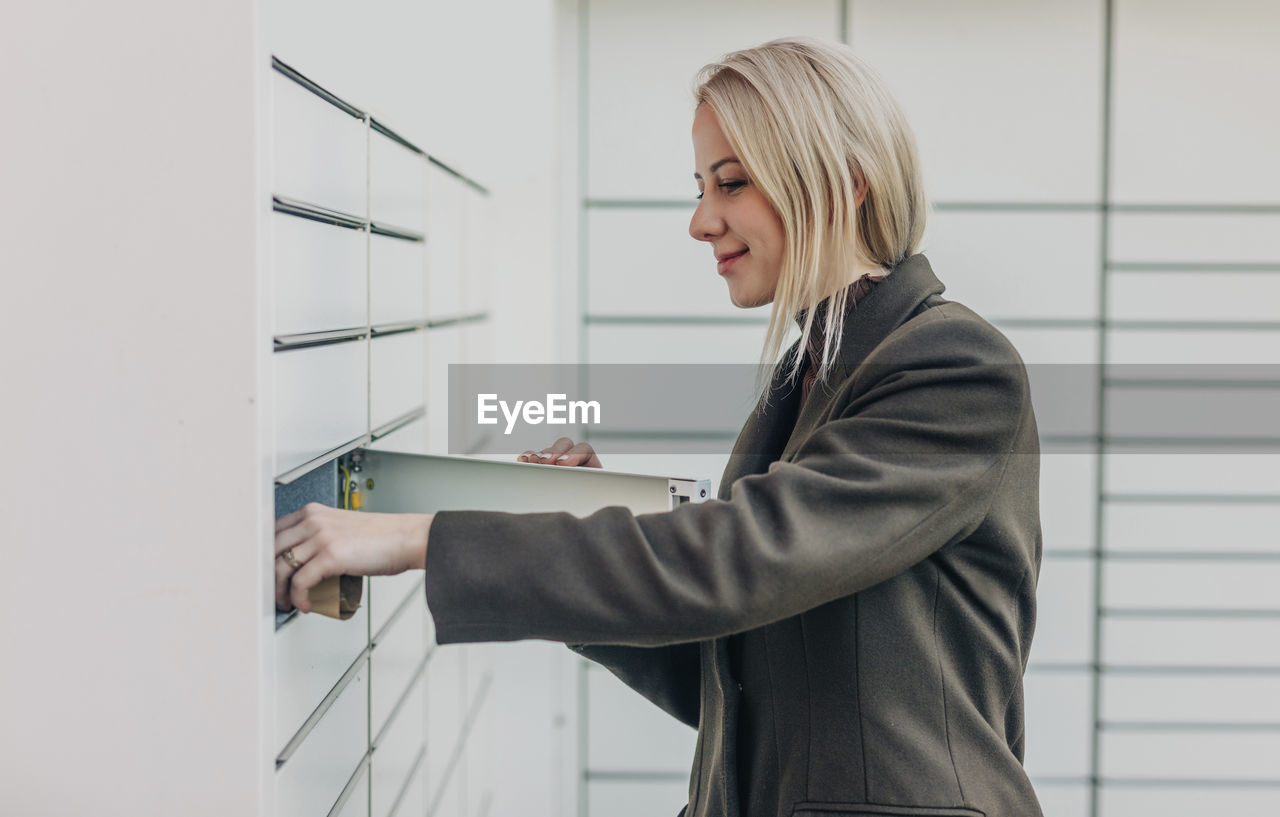 Smiling woman receiving parcel from parcel locker