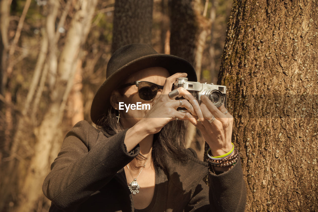 Woman photographing near tree trunk