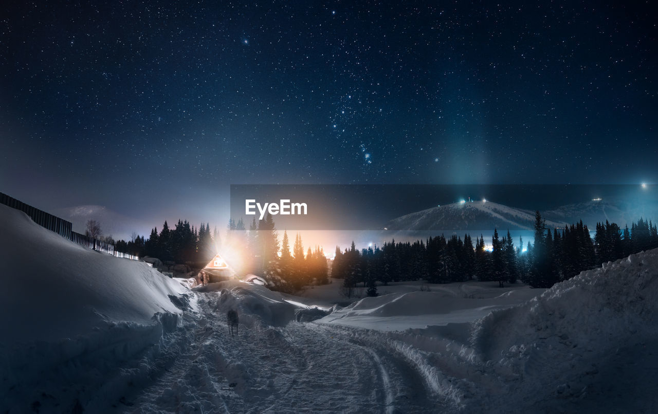 Panoramic view of illuminated snowcapped mountains against sky at night