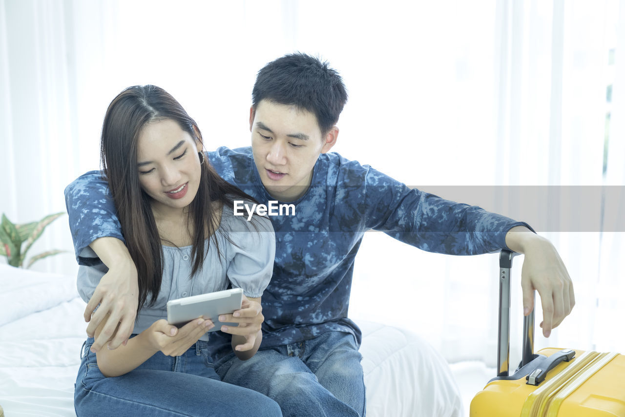 YOUNG COUPLE LOOKING AWAY WHILE SITTING ON LAPTOP