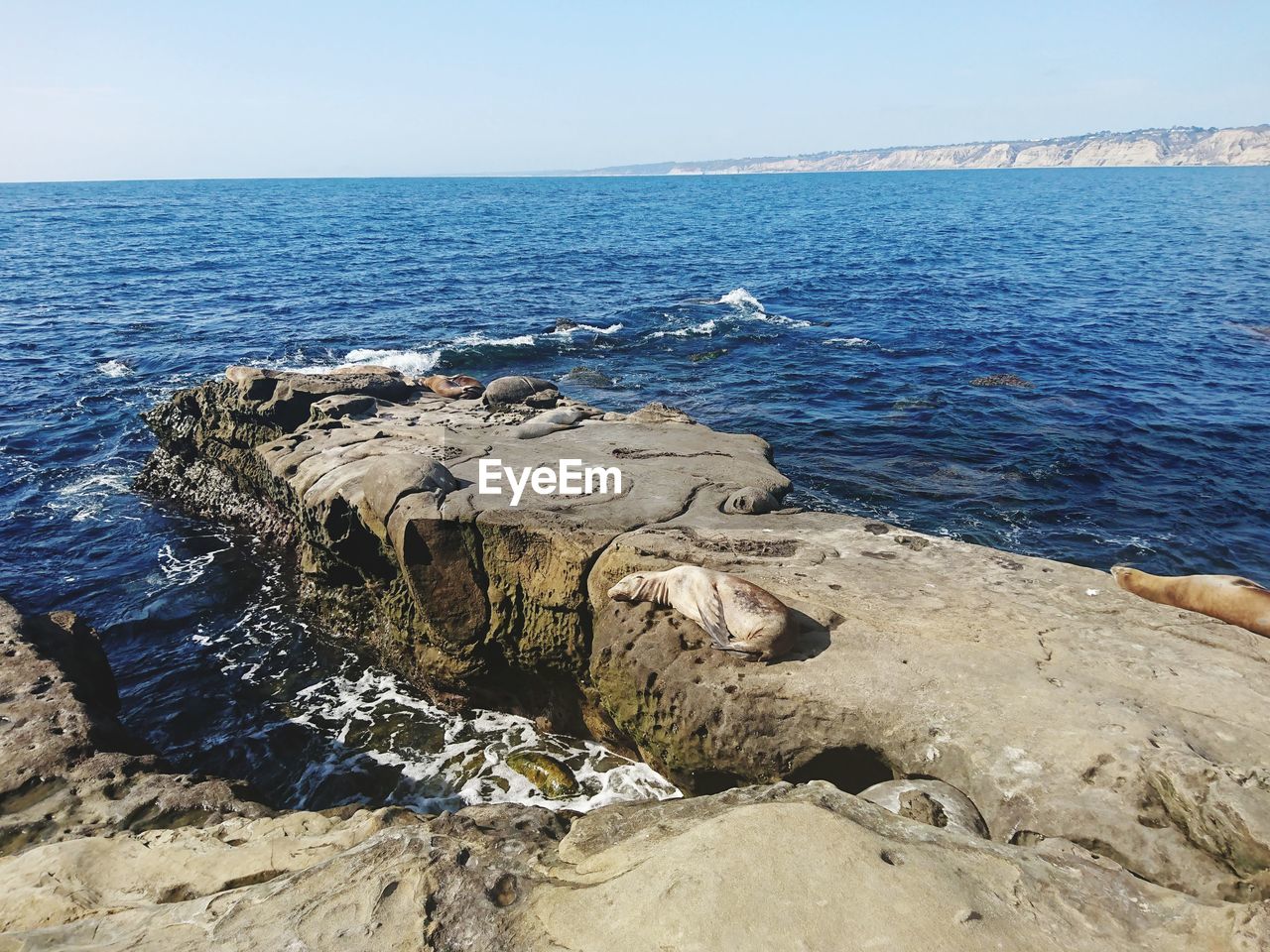 ROCKS BY SEA AGAINST SKY