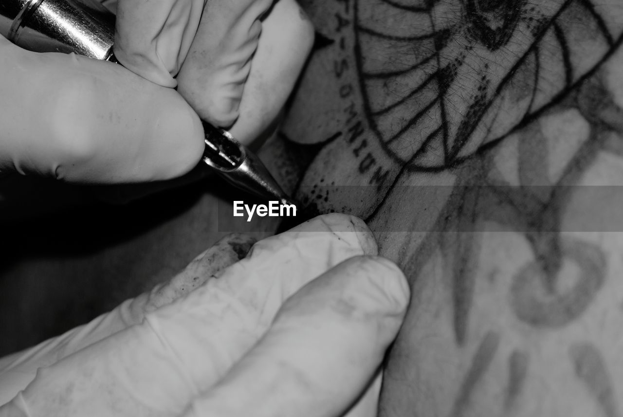 Cropped hands of artist making tattoo