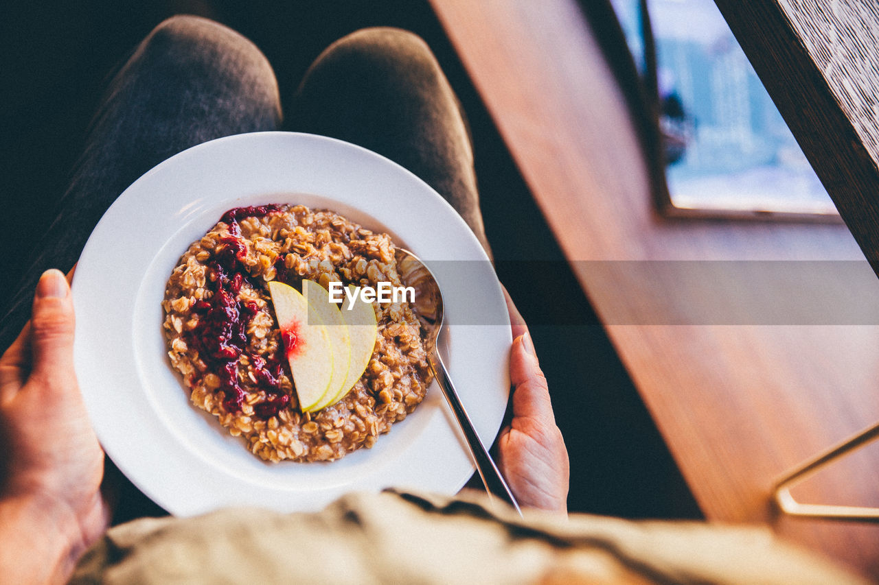 Midsection of person holding porridge on plate on lap