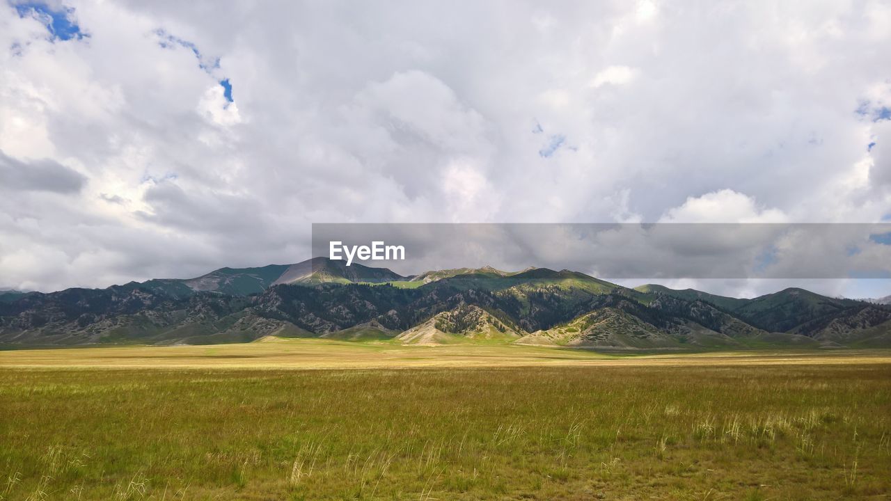 SCENIC VIEW OF FIELD BY MOUNTAINS AGAINST SKY