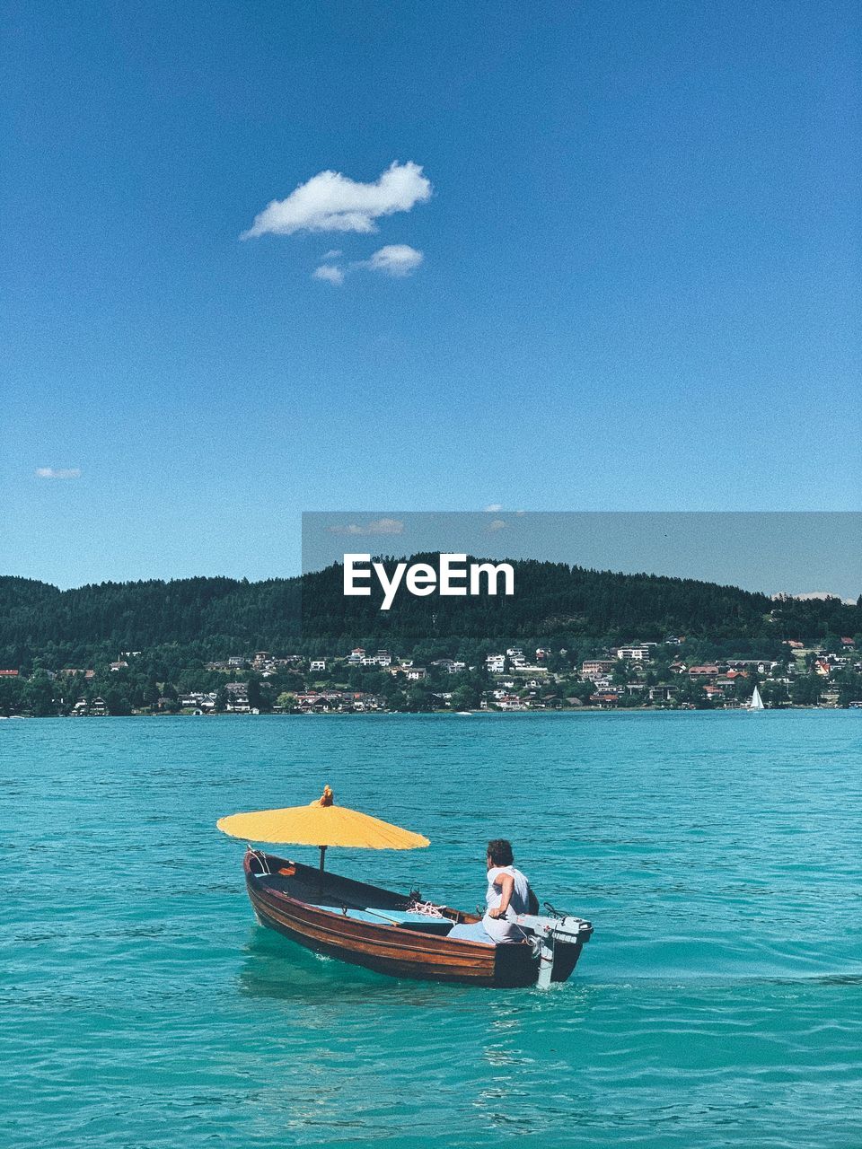 MAN ROWING BOAT IN SEA AGAINST SKY