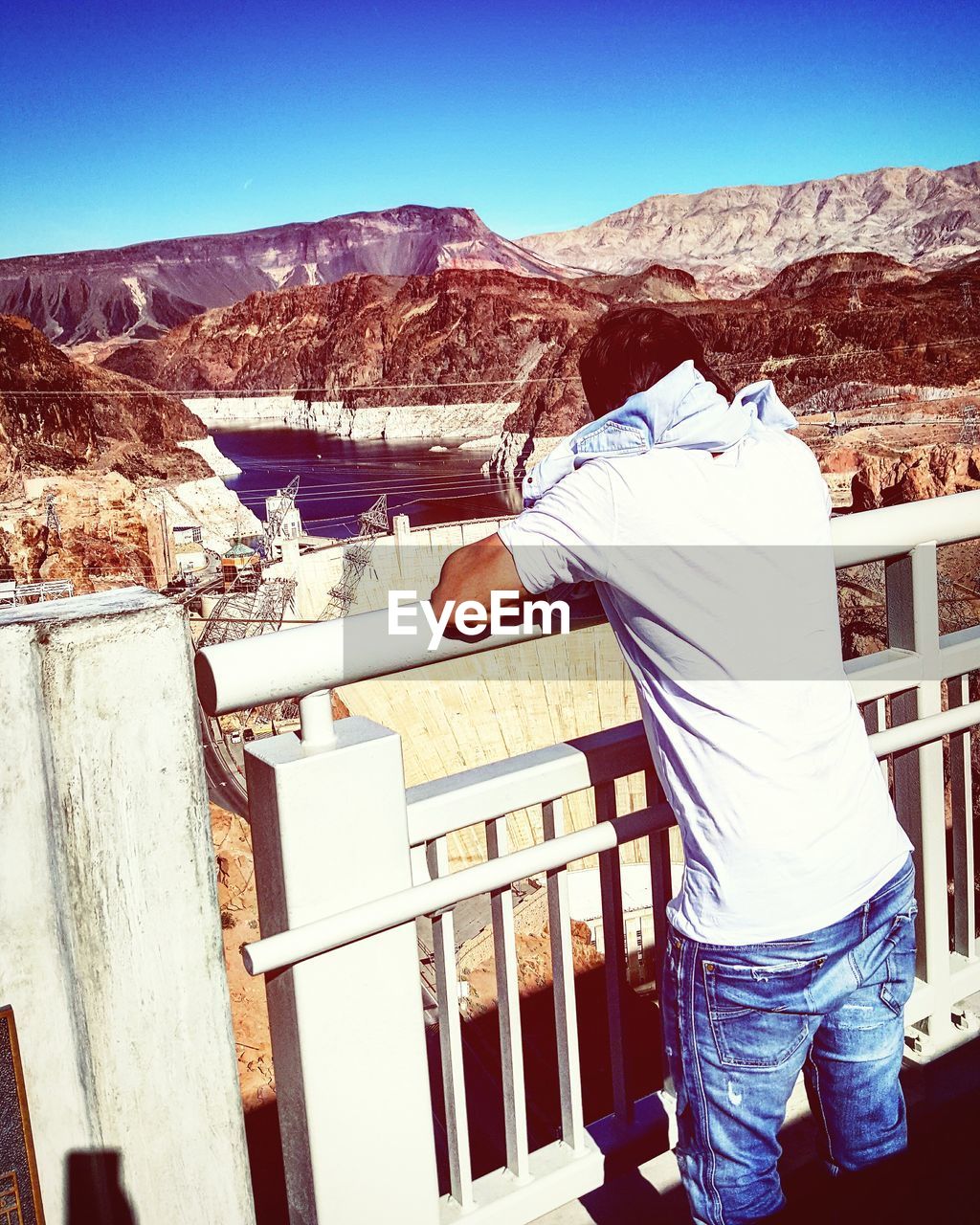 Rear view of man leaning on railing at hoover dam