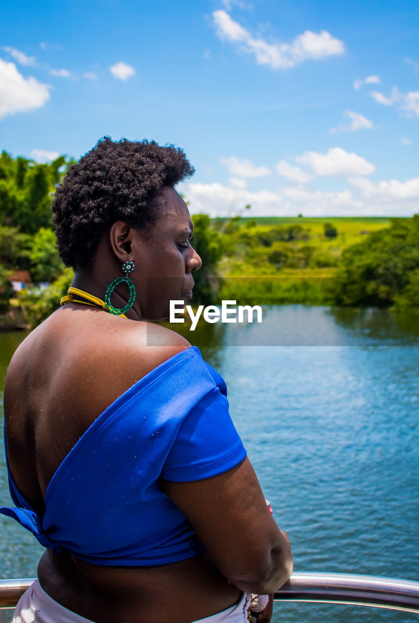 Side view of woman standing by railing over infinity pool