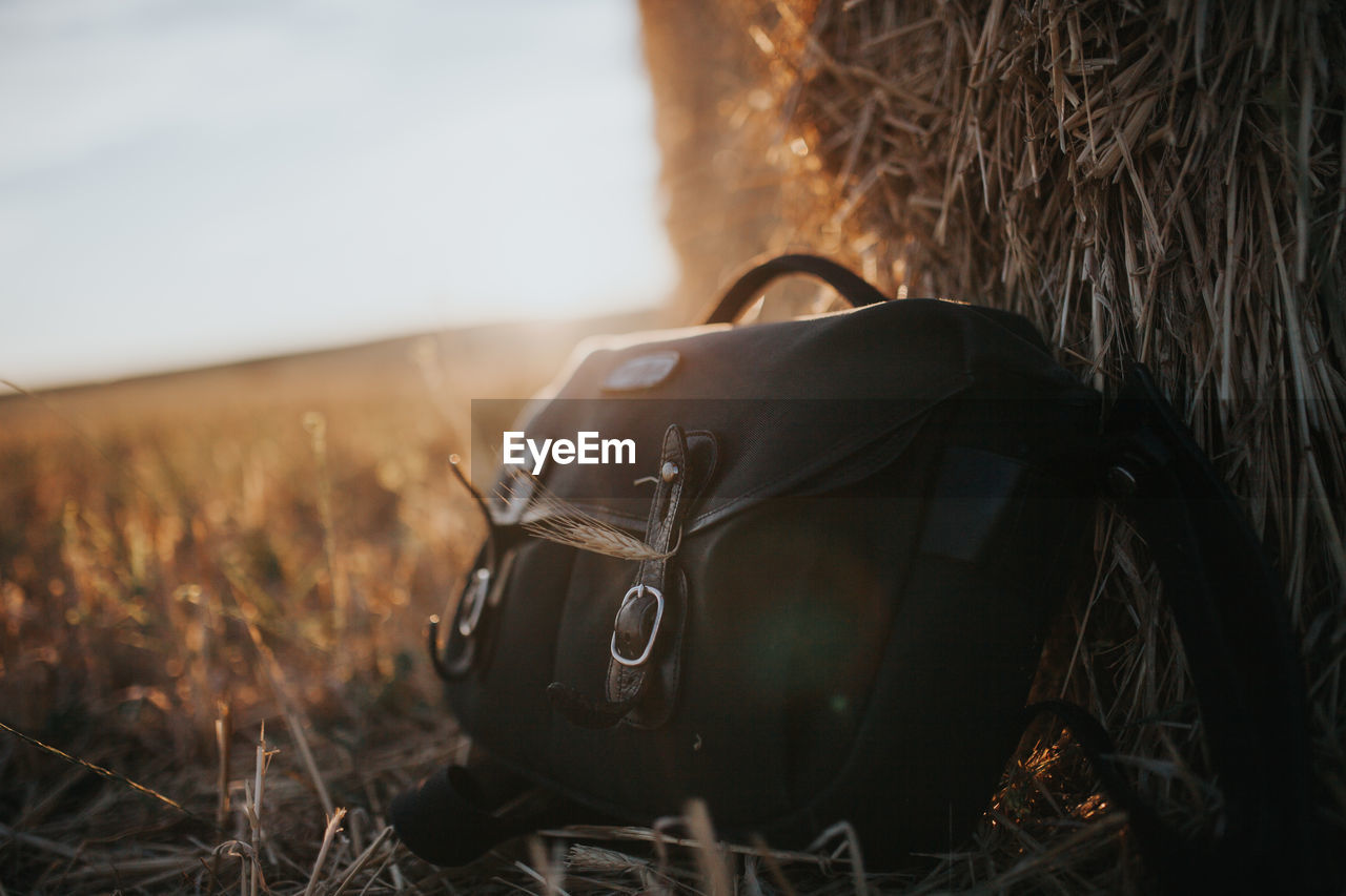 Close-up of bag by hay bale on field