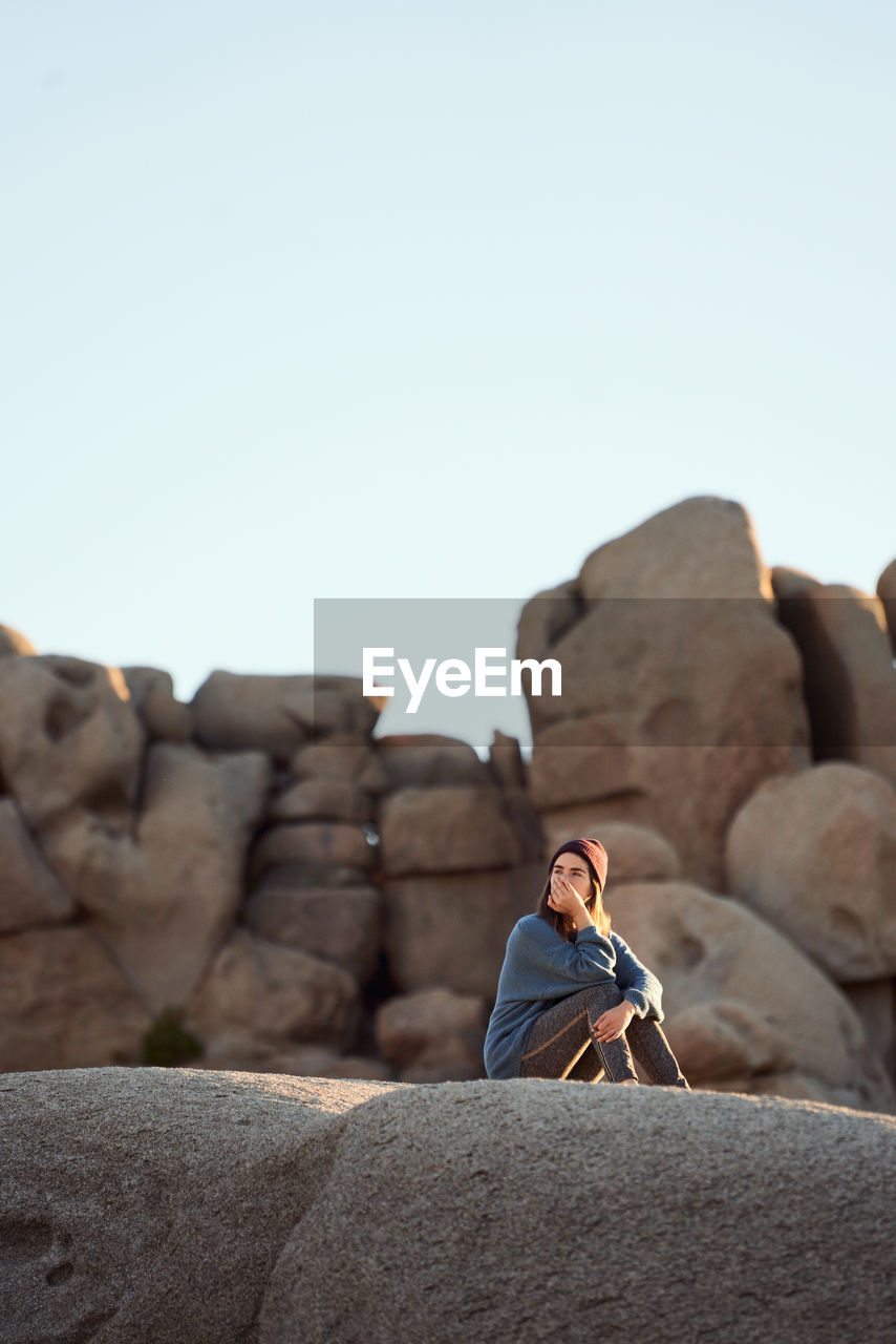 Young woman sitting on rocks contemplating