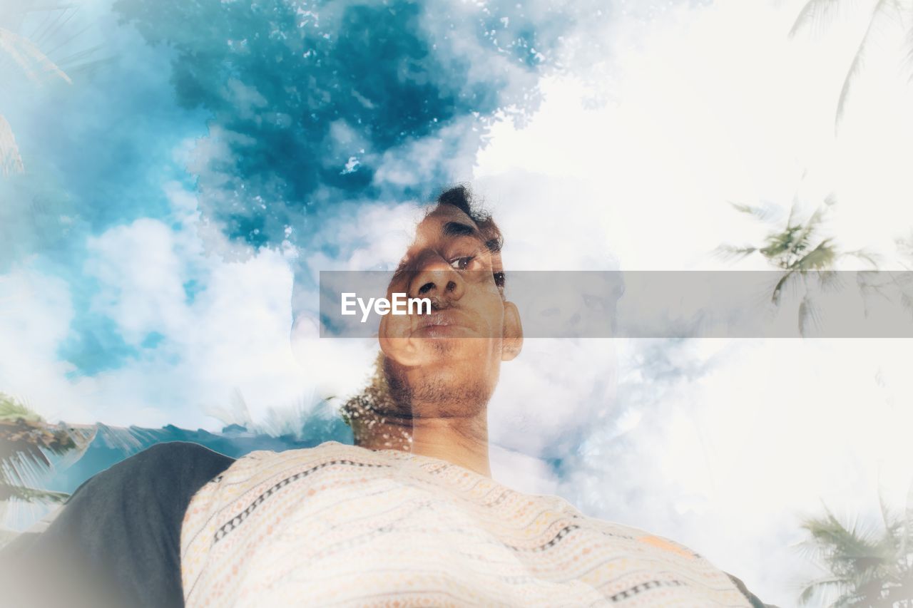 Double exposure of young man and cloudy sky