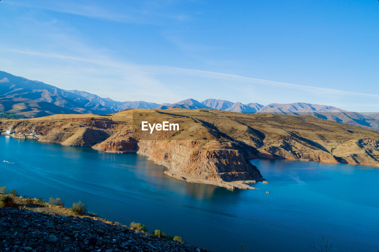 Scenic view of lake and mountains against blue sky