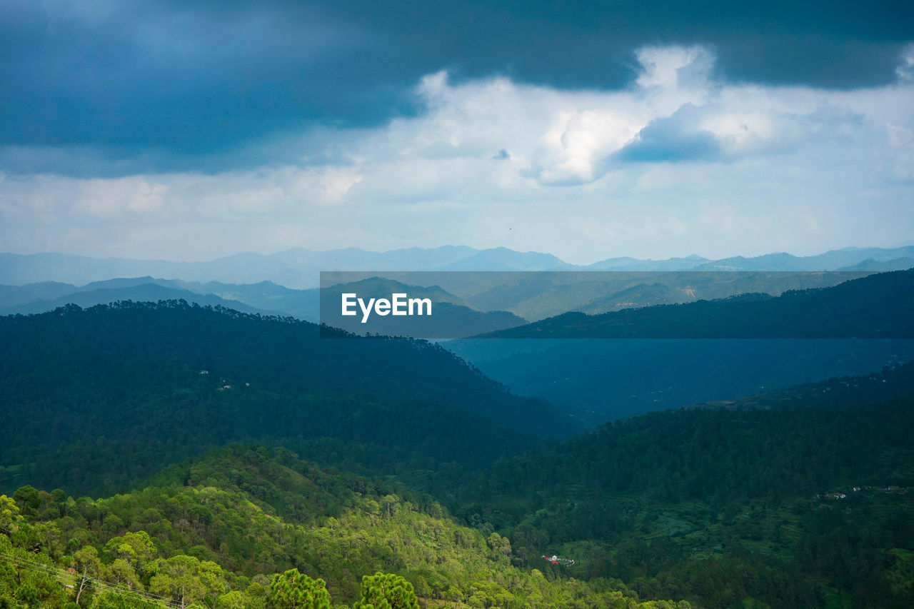A beautiful and soothing landscape of mountains covered in clouds and green trees during winters.