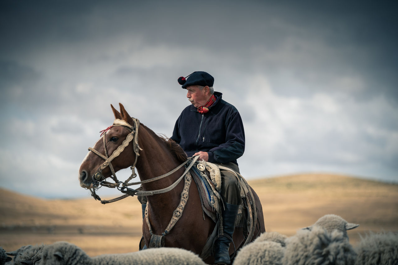 MAN RIDING HORSE ON CLOUDY SKY