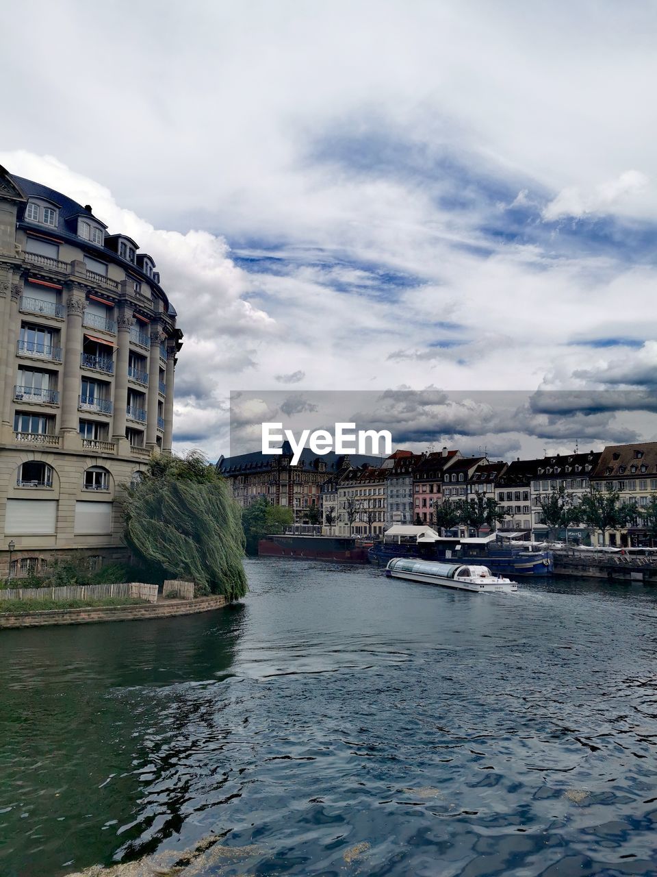 Buildings by river against sky in city