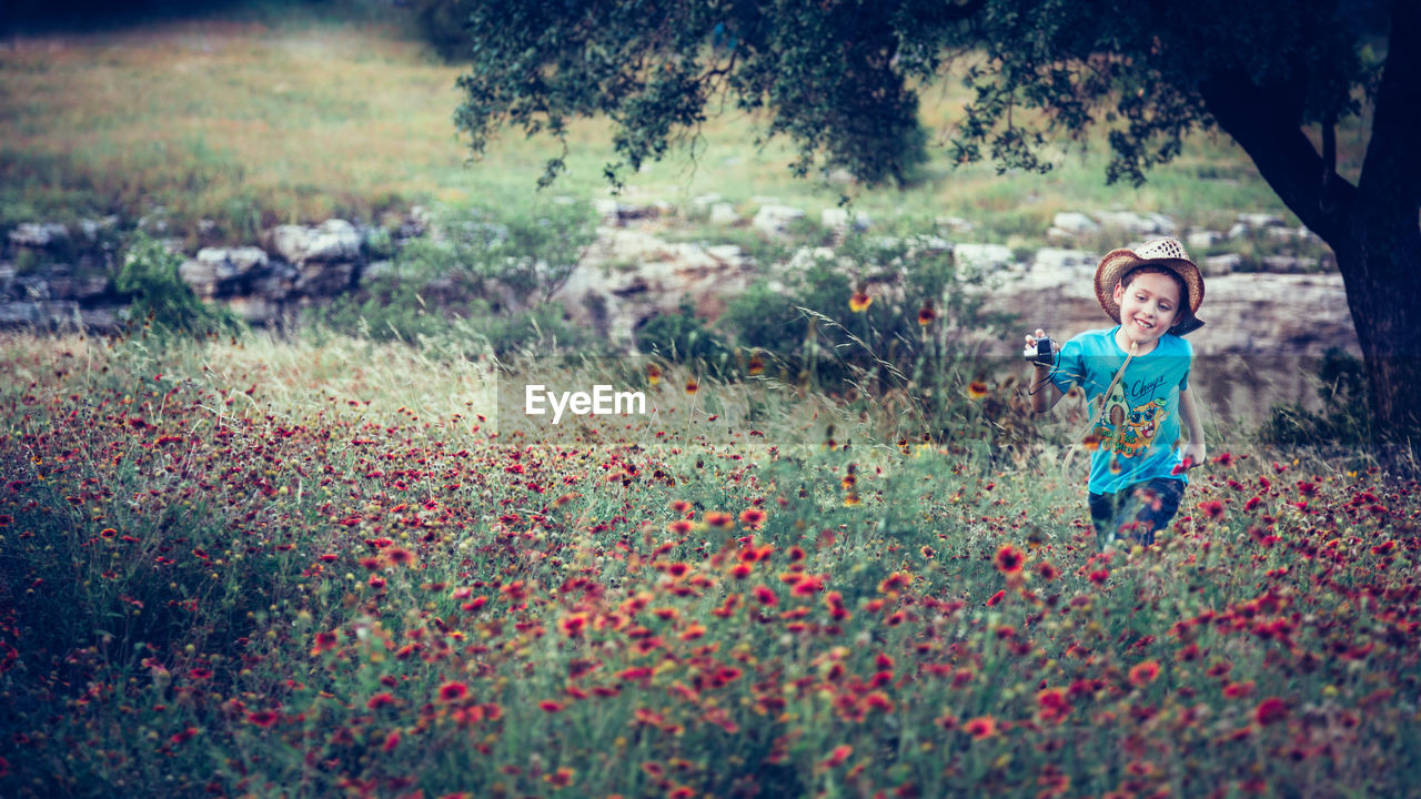 Smiling girl standing amidst flowers in field