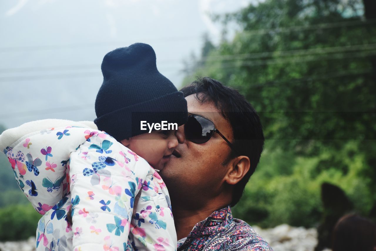 Close-up of father kissing baby outdoors