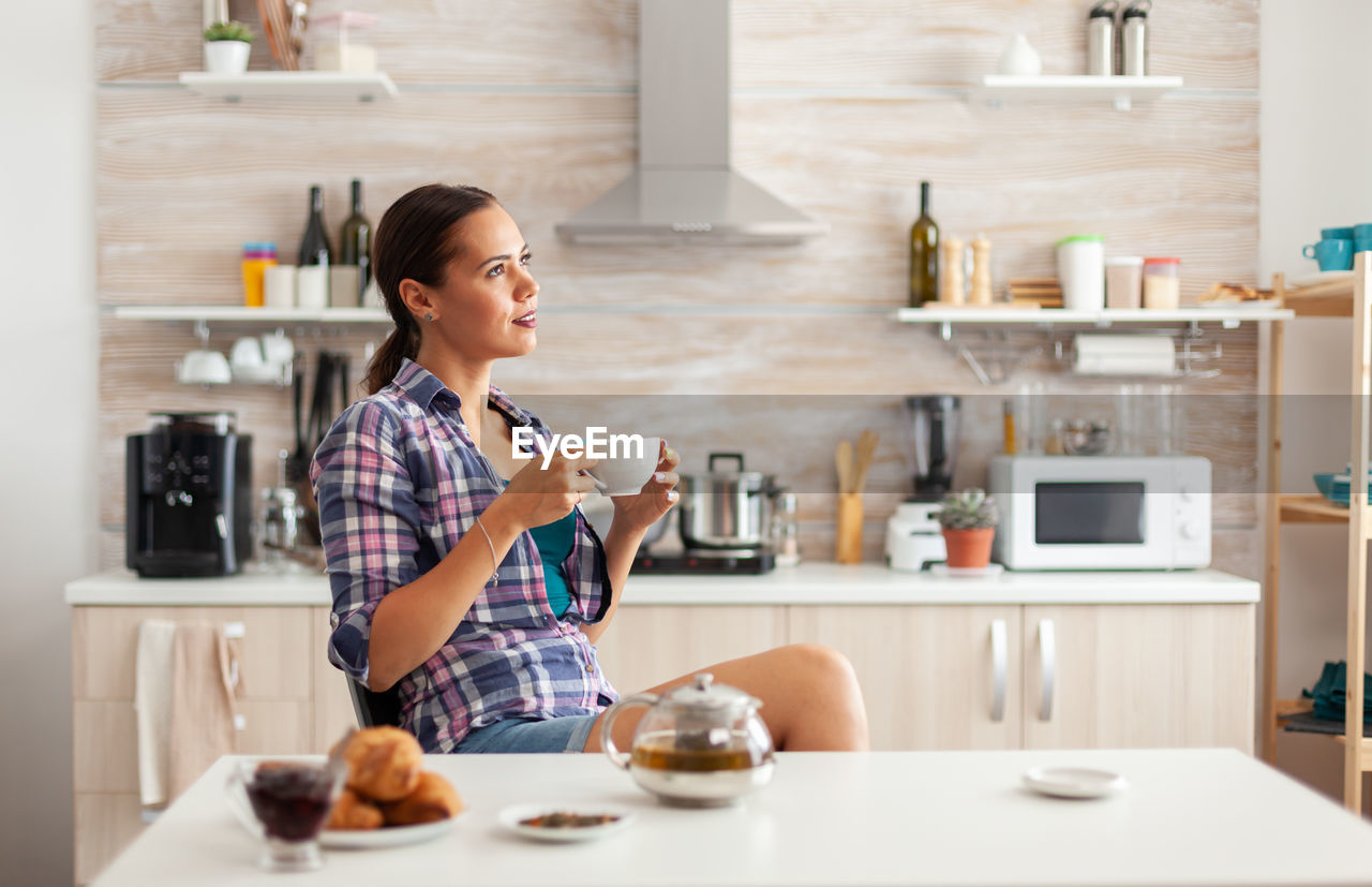 portrait of young woman using mobile phone while sitting at table