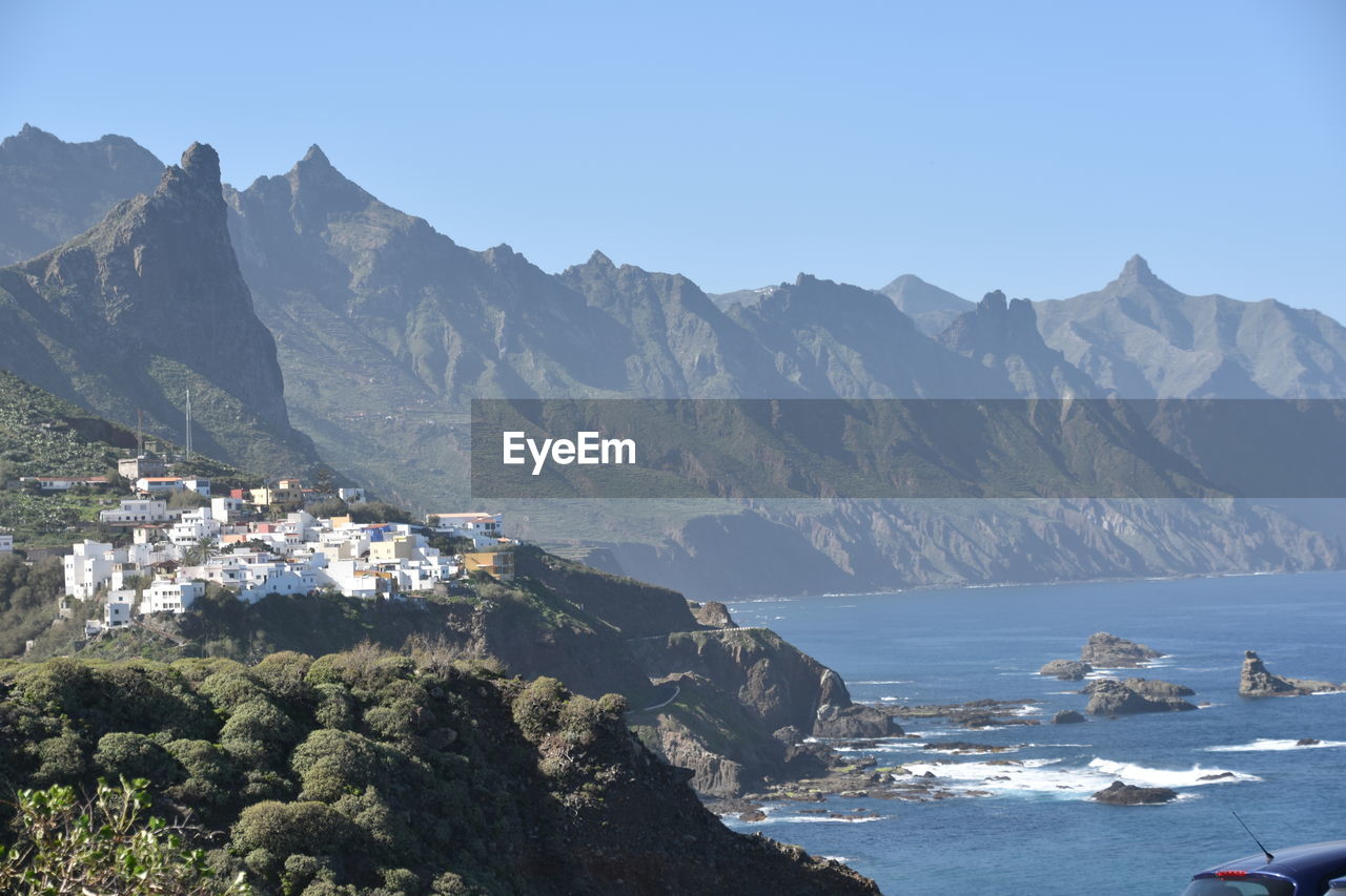 Scenic view of sea and mountains against clear sky