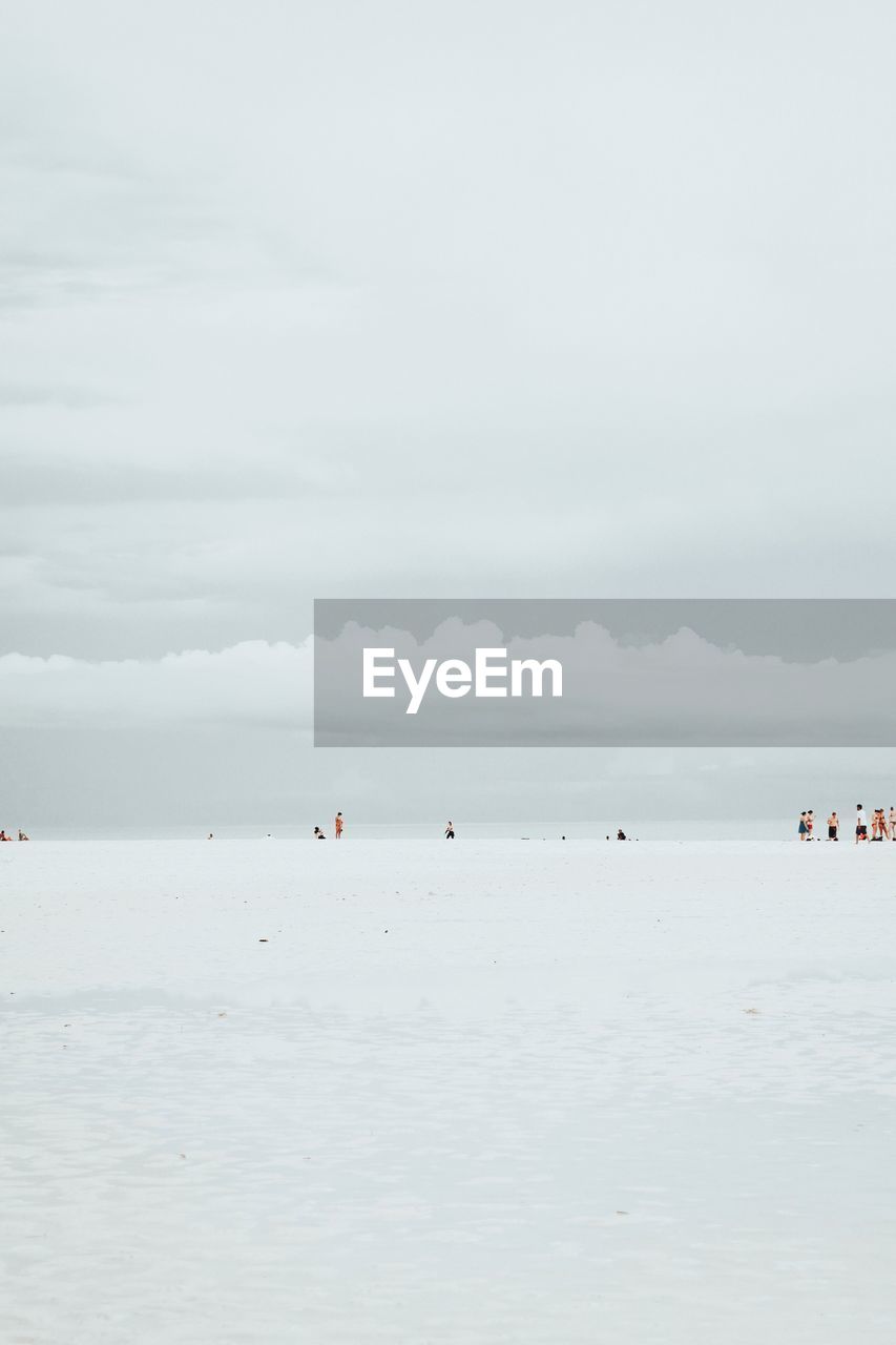 People at beach against sky during winter