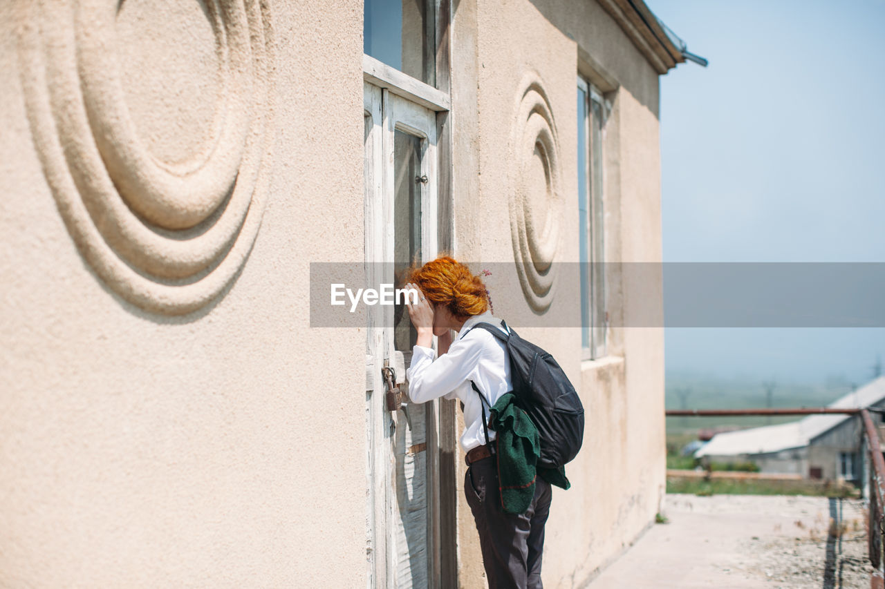 Side view of woman peeking through house door