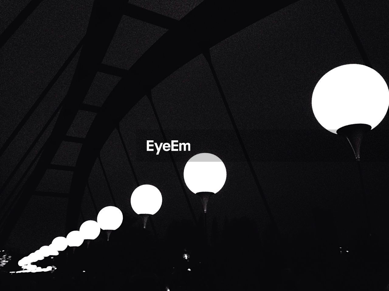 Low angle view of illuminated street light on bridge at night