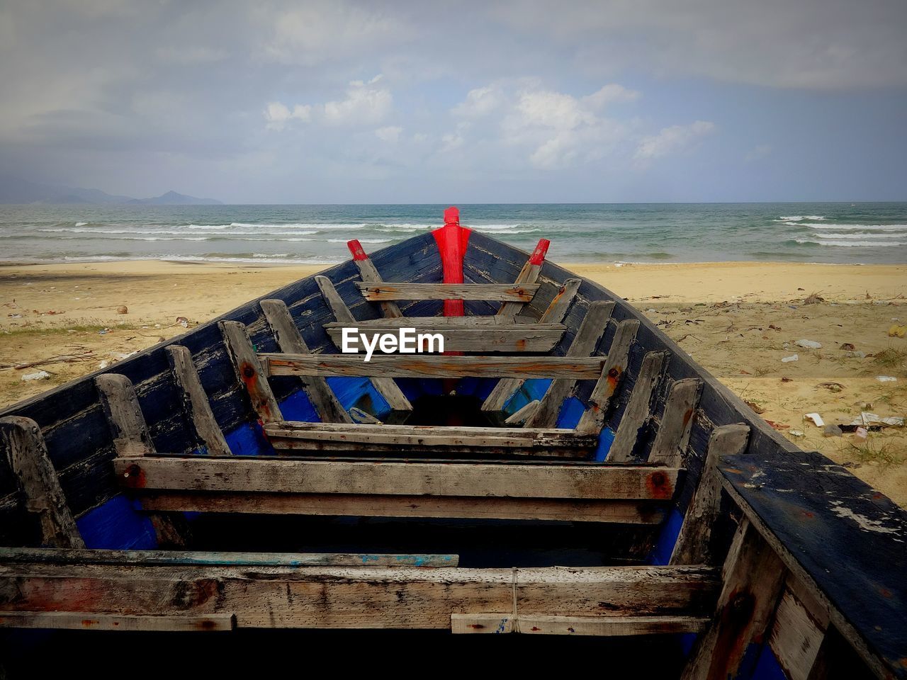 Boat moored at beach against sky