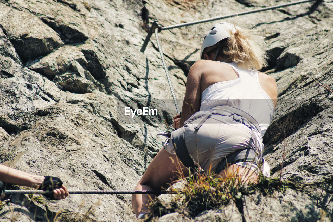Low angle view of woman climbing rock